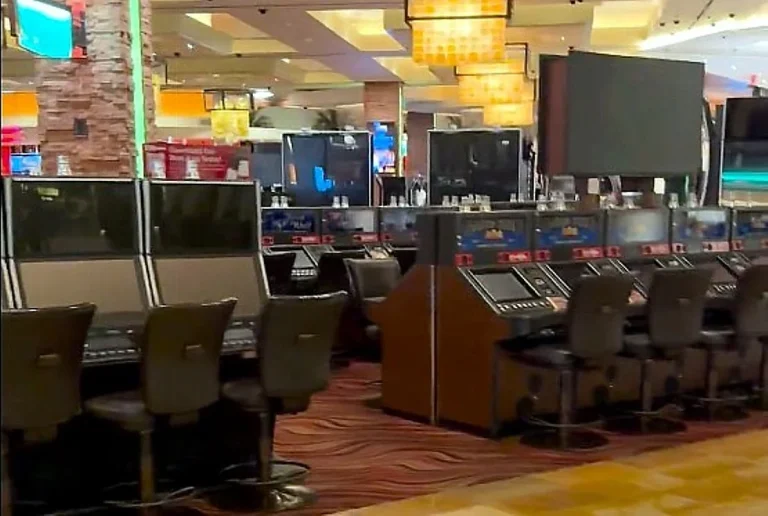 Vista del piso del casino Red Rock Resort durante un apagón, con máquinas tragamonedas oscuras y personal asistiendo a los clientes bajo iluminación de emergencia.