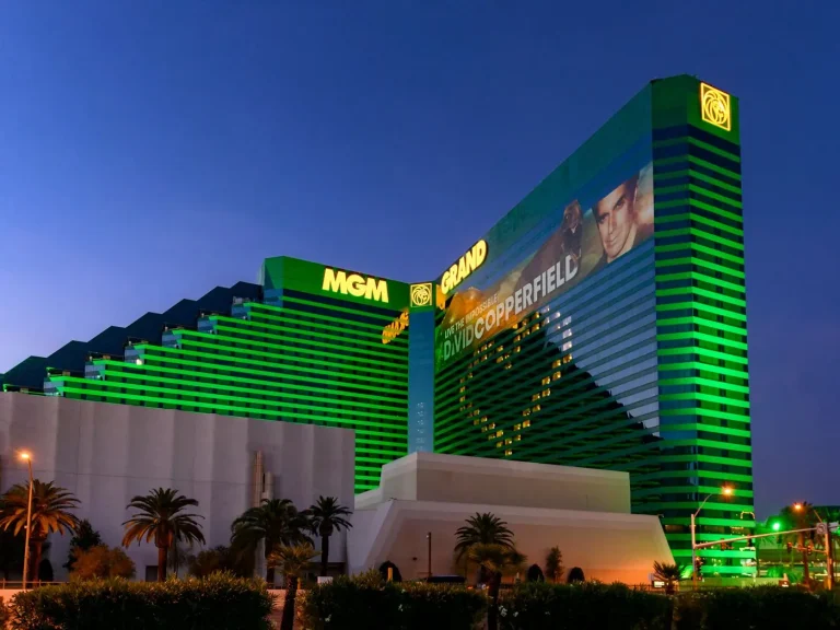 Interior de una lujosa habitación de hotel en Las Vegas, con una mano usando una aplicación de apuestas deportivas en un teléfono y un boleto de apuesta falsificado en la pantalla.