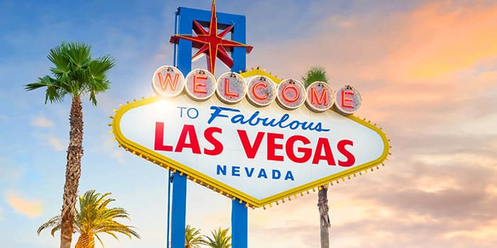 Un cartel de bienvenida a Las Vegas con menos personas de lo habitual, simbolizando la disminución del turismo, con un ícono de redes sociales superpuesto en señal de advertencia.